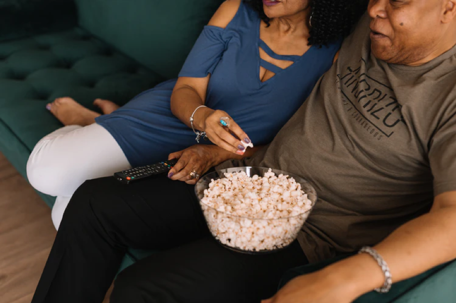 Couple sitting on the sofa relaxing watching a film with a bowl of popcorn