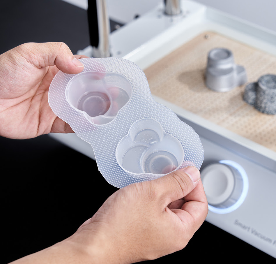 Hands holding a plastic mould formed by a vacuum former.