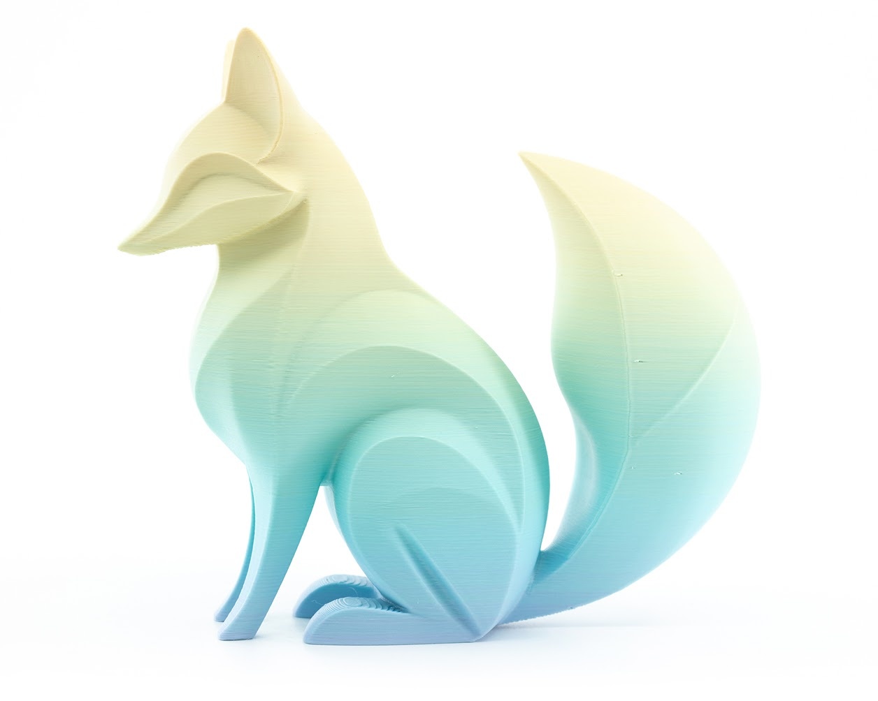 Una figurita decorativa de un zorro en estilo low-poly, impresa en 3D con filamento PLA multicolor con degradado de colores del arcoíris.