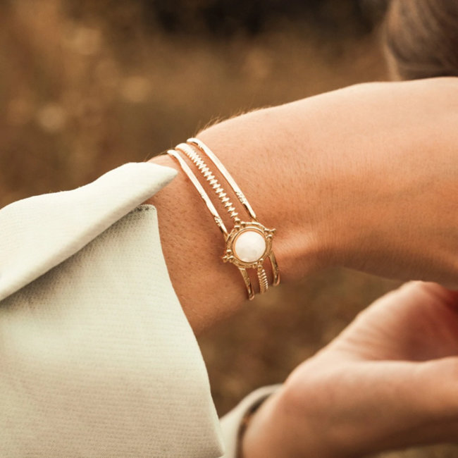 Brede goud armband met witte steen