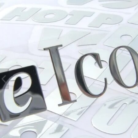 Chrosomax, In metaal gevormde vernikkelde dunne logo's of teksten voorzien van dubbelzijdig tape.