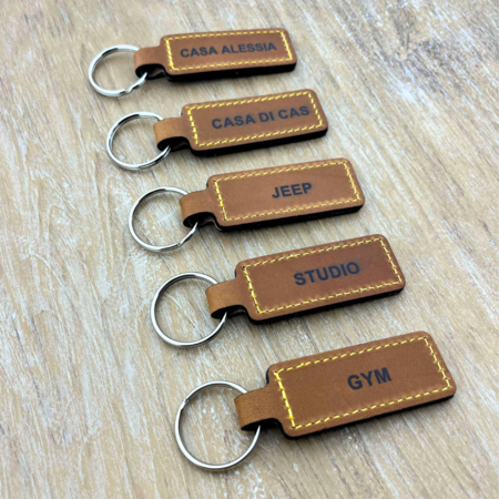 Sleutelhanger van leer of kunstleer 23x95mm met tekst of nummering zwart gedrukt - per 1 stuk