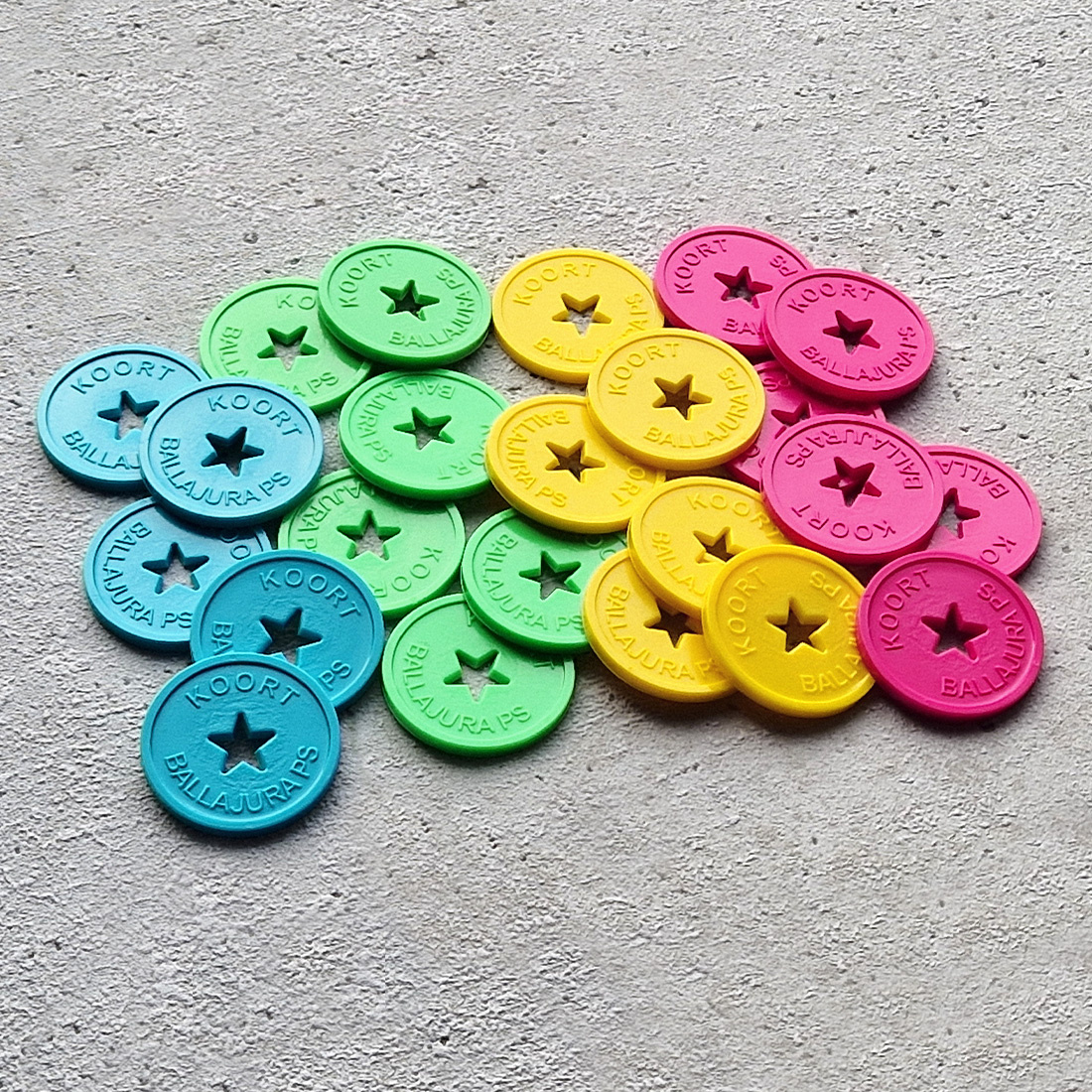 Overview gekleurde plastic reliëfmunten in vier kleuren met gat in stervorm