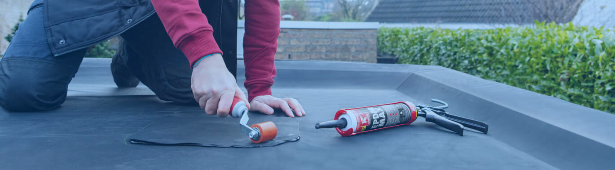 Bodemlijm met roller aanbrengen op een vlak EPDM dakoppervlak.