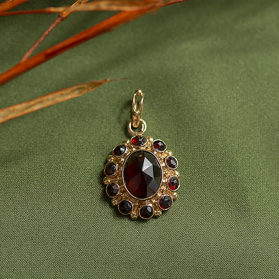 Gold entourage pendant with garnet