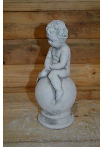Betonnen jongetje zittend op bol 