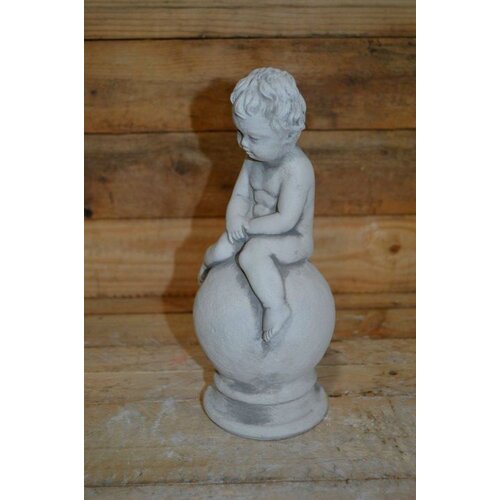 Betonnen jongetje zittend op bol 