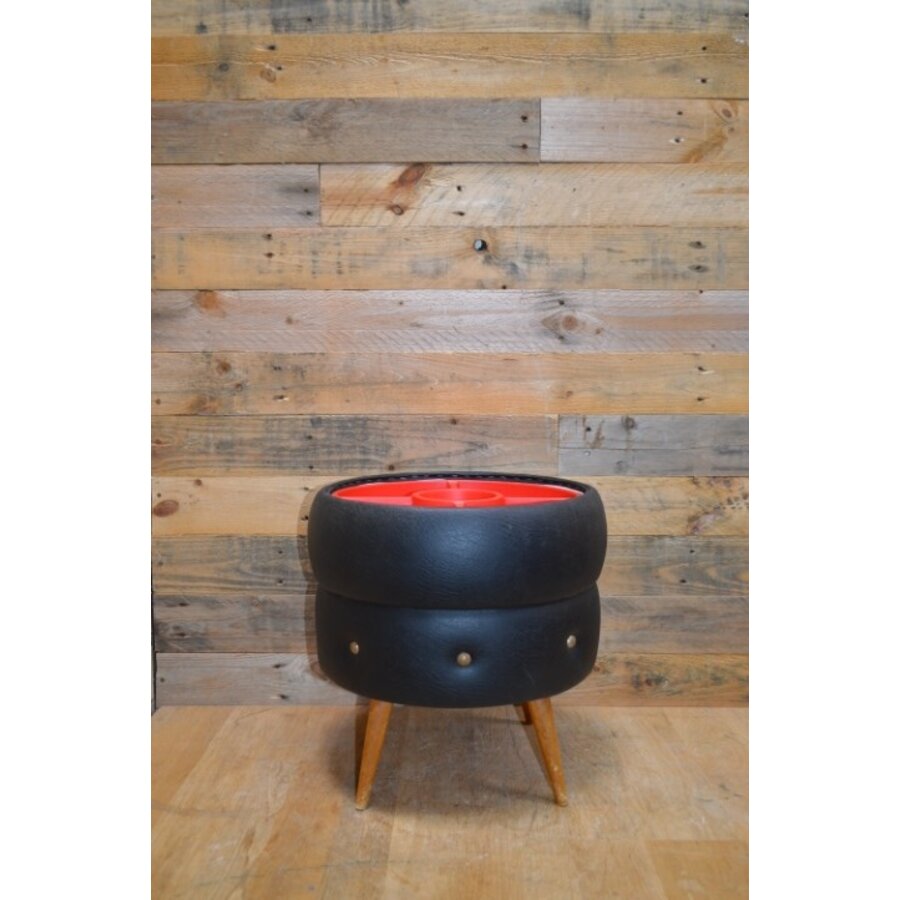 Retro poef zwart skai met rode kunststof verdeler, houten pootjes jaren ’60-2