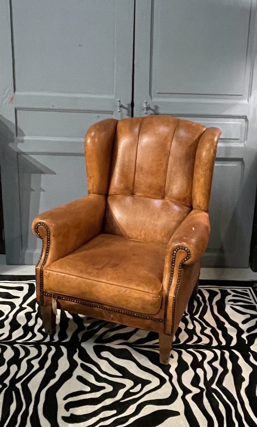 Bijna antieke leren oorfauteuil met leuke details