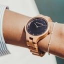 La Collection AURORA est inspirée par l'air et les paysages de la nature Scandinave. Cette montre légère est fabriquée avec du bois d'Olivier Européen et comporte un cadran en acier inoxydable noir de jais et des détails rose dorés. Le bracelet est dispon