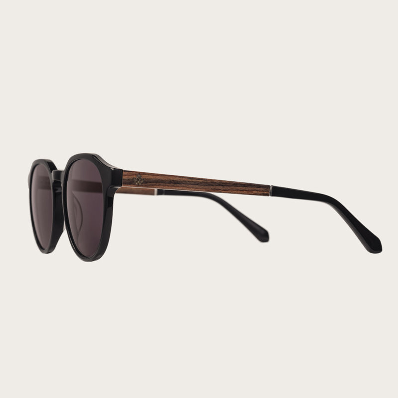 REVELER All Black sfoggia un'elegante montatura nera geometrica con lenti scure. In resistente bio-acetato italiano firmato Mazzucchelli con stanghette in palissandro naturale rifinite a mano e terminali neri in acetato. Il bio-acetato è ricavato dal coto