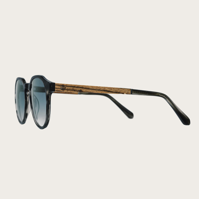 The REVELER Heritage Gradient Blue features a sleek geometric grey tortoise frame with gradient blue lenses. Composed of durable Italian Mazzucchelli bio-acetate with hand-finished natural zebrawood temples and tortoise acetate tips. Bio-acetate is made f