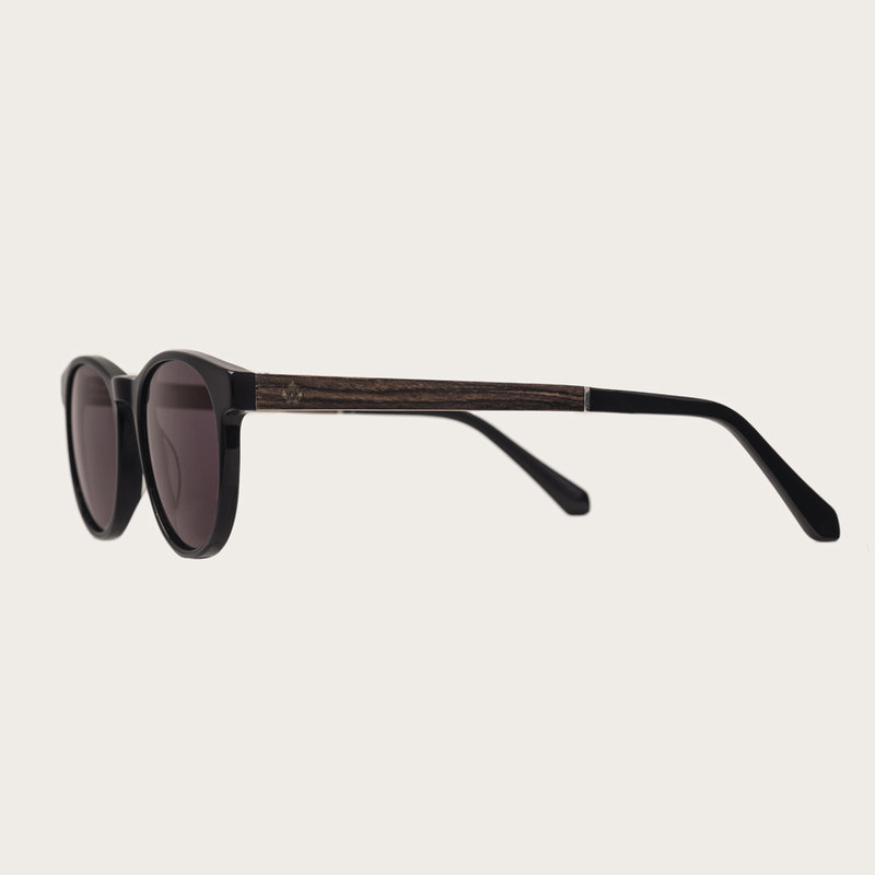 La paire de lunettes l’ELLIPSE All Black poséde un cadre rond en noir avec des verres en noir. Fabriquée à partir de bois durable et du bioacétate Mazzuchelli Italien avec des branches et écaille de tortue en bois de rose et des manchons en acétate noir.