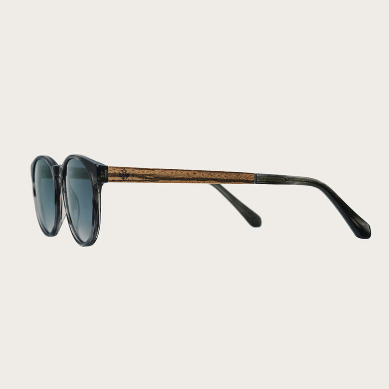 "La paire de lunettes l’ELLIPSE Heritage Gradient Blue poséde un cadre rond en écaille gris avec des verres en bleu dégradé. Fabriquée à partir de bois durable et du bioacétate Mazzuchelli Italien avec des branches de bois zèbre naturel et des manchons en