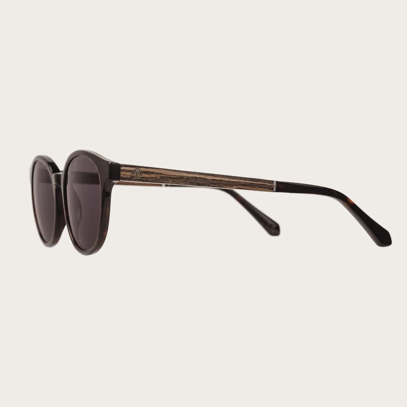 La paire de lunettes le SOHO Forever Havanas Black poséde un cadre ovale en marron foncé avec des verres en noir. Fabriquée à partir de bois durable et du bioacétate Mazzuchelli Italien avec des branches et écaille de tortue en ébène et manchons en acétat