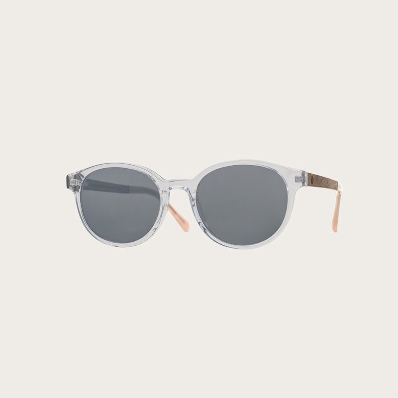 La paire de lunettes le SOHO Clear Smoke poséde un cadre ovale claire avec des verres en gris fumé et fabriquée à partir de bois durable et du bioacétate Mazzuchelli Italien avec des branches de senna siamea naturel en bois et des manchons en acétate nude