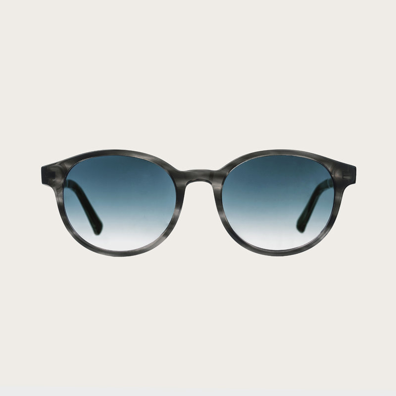 The SOHO Heritage Gradient Blue features an oval grey tortoise frame with gradient blue lenses. Composed of durable Italian Mazzucchelli bio-acetate with hand-finished natural zebrawood temples and tortoise acetate tips. Bio-acetate is made from cotton an