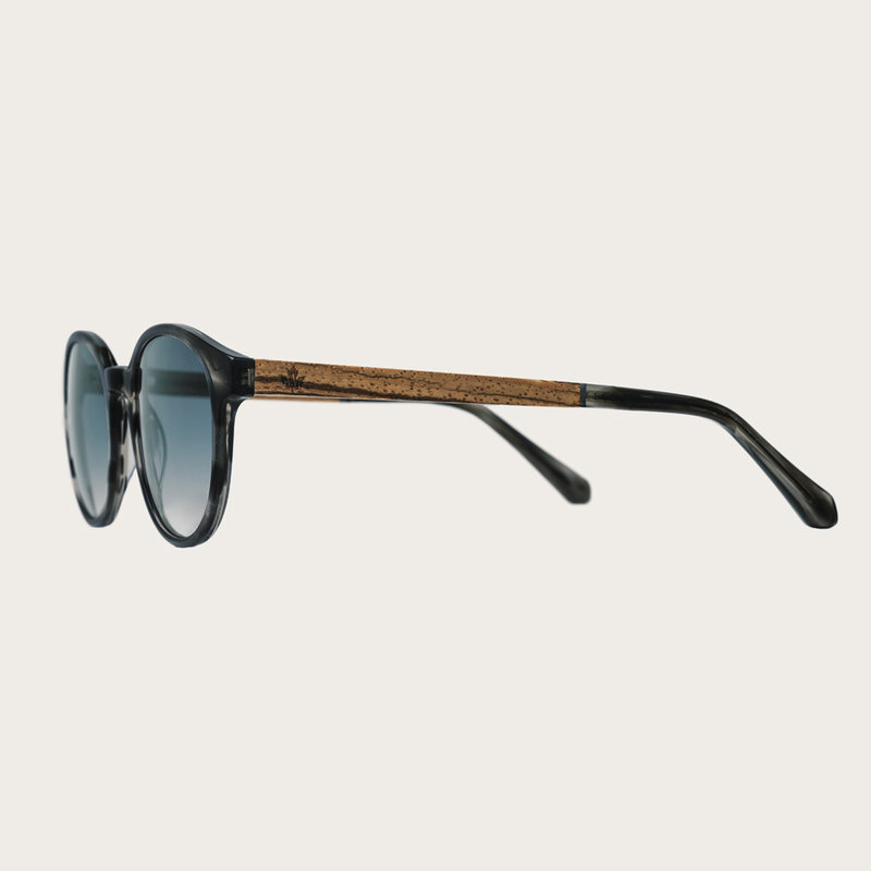 The SOHO Heritage Gradient Blue features an oval grey tortoise frame with gradient blue lenses. Composed of durable Italian Mazzucchelli bio-acetate with hand-finished natural zebrawood temples and tortoise acetate tips. Bio-acetate is made from cotton an