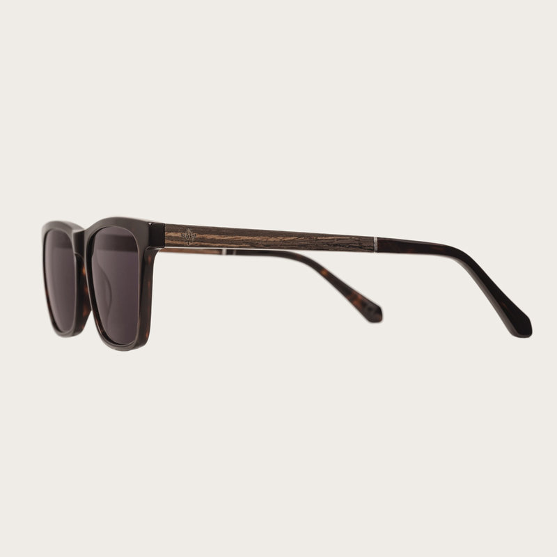 La paire de lunettes BROOKLYN Forever Havanas Black poséde un cadre carré en écaille marron foncé avec des verres en noir. Fabriquée à partir de bois durable et du bioacétate Mazzuchelli Italien avec des branches et écaille de tortue en ébène et manchons