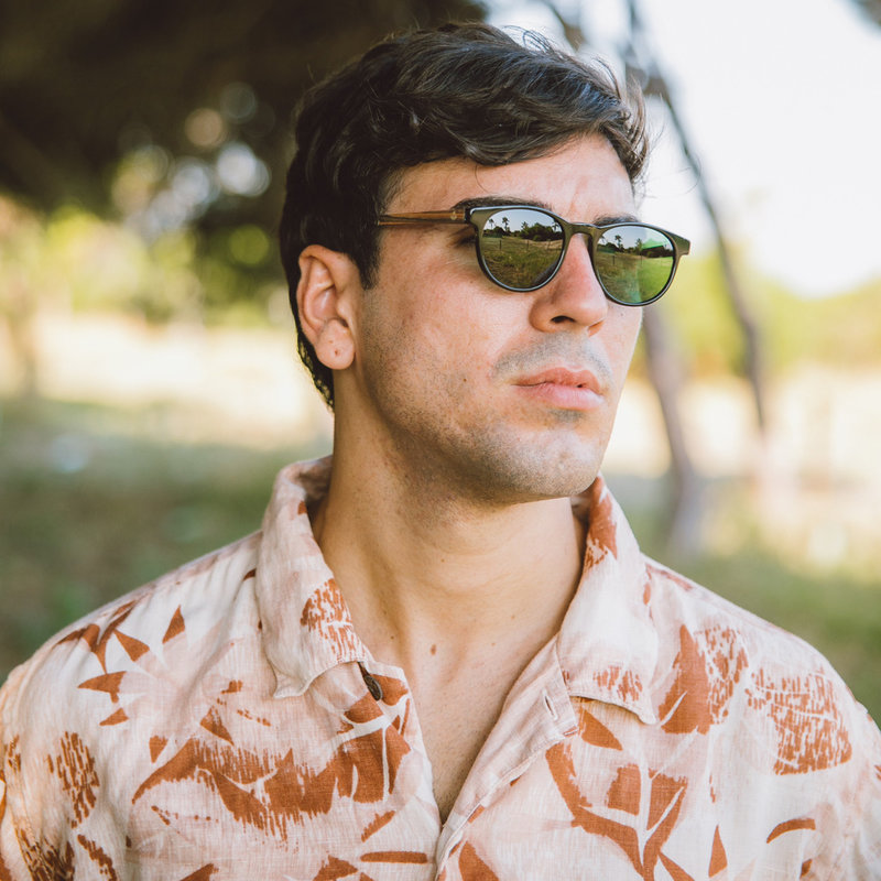 "La paire de lunettes l’ELLIPSE Black Camo poséde  un cadre rond en noir avec des verres en camouflage vert. Fabriquée à partir de bois durable et du bioacétate Mazzuchelli Italien avec des branches et écaille de tortue en bois de rose et des manchons en