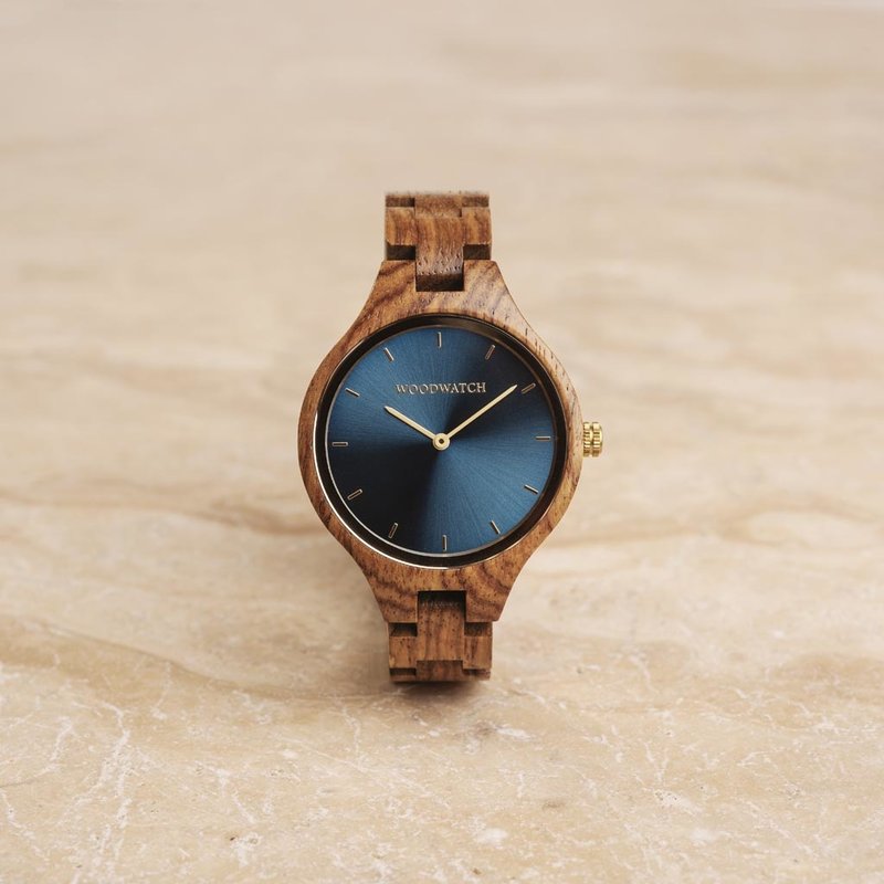 La colección AURORA transpira el aire fresco de la naturaleza escandinava y los espectaculares cielos. Este liviano reloj está hecho de Madera de madera de kosso, y va acompañado de una azul esfera de acero inoxidable y con detalles en color dorado.<br />
El r