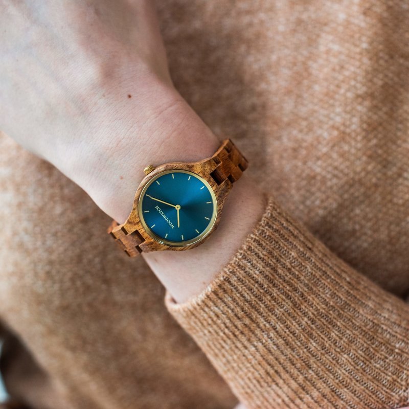 Die Herrenuhr CLASSIC Sailor hat ein schlankes und elegantes Gehäuse und verfügt über eine einzigartige Mondphasenanzeige sowie zwei zusätzliche Hilfszifferblätter. Die aus ostafrikanischem Kosso-Holz gefertigte Uhr mit blauem Zifferblatt und goldenen Det