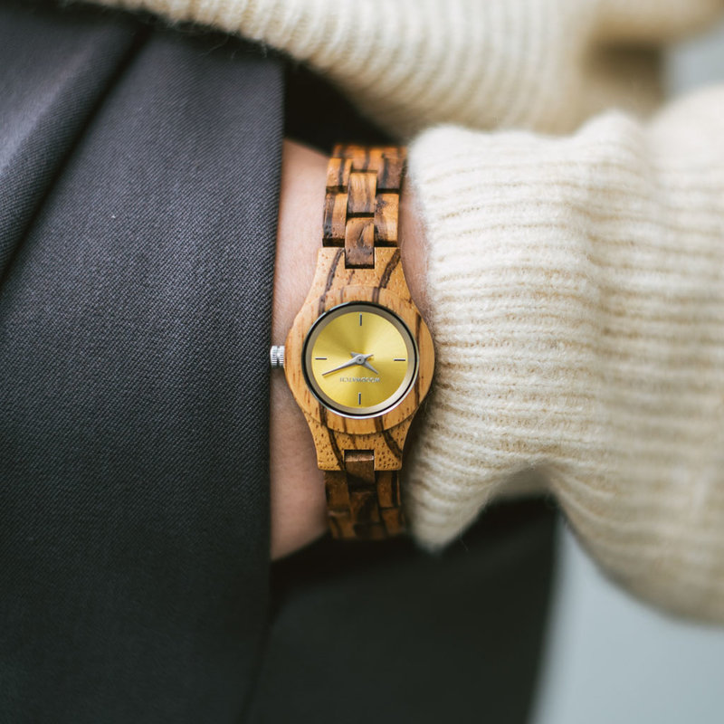 La montre Senna de la collection FLORA est composée de bois lisse Zingana finement travaillé à la main. Le modèle Senna comporte un jaune avec des détails de couleur argentée.