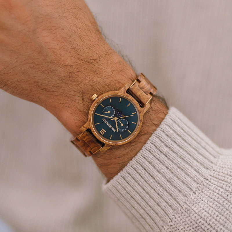 El reloj CLASSIC Sailor para hombre tiene una elegante caja delgada a la vez que presenta un movimiento de fase lunar único y dos subesferas adicionales. El reloj está hecho de madera Kosso de África Oriental y presenta una esfera azul y detalles en color