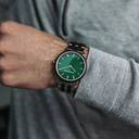 Een nieuw MINIMAL design met een tijdloze uitstraling die past bij elke gelegenheid. Het horloge heeft een slanke, stalen kast, lunette van loodhout en groene wijzerplaat. Wordt geleverd met een volledig nieuw ontworpen horlogeband, die qua stijl en mater