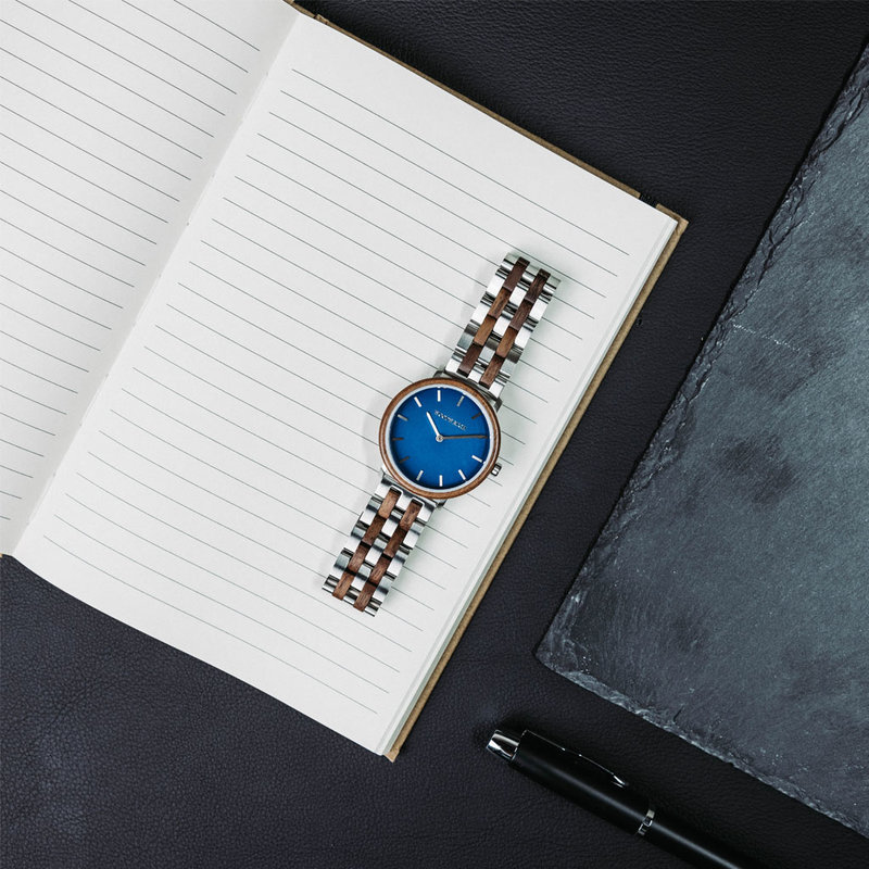 Un design MINIMAL repensé avec un look intemporel qui s'adapte à toutes les occasions. La montre est dotée d'un boîtier fin en acier, d'une lunette en noyer et d'un cadran bleu. Elle est livrée avec un nouveau bracelet de montre, conçu dès le départ pour