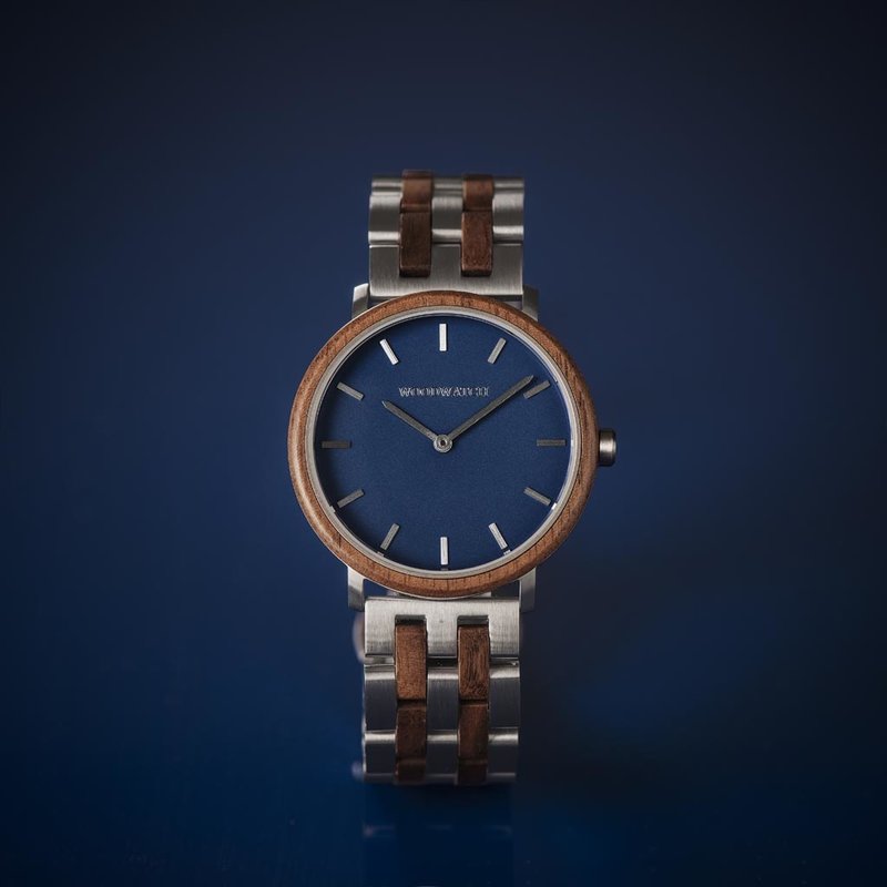 Un design MINIMAL repensé avec un look intemporel qui s'adapte à toutes les occasions. La montre est dotée d'un boîtier fin en acier, d'une lunette en noyer et d'un cadran bleu. Elle est livrée avec un nouveau bracelet de montre, conçu dès le départ pour