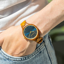 The AURORA Collection breaths the fresh air of Scandinavian nature and the astonishing views of the sky. This light weighing watch is made of kosso wood, accompanied by a blue stainless-steel dial with golden details.<br />
Comes with a cactus leather strap in