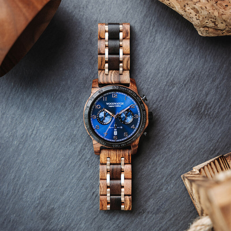 Die CLASSIC Sailor hat ein schlankes und elegantes Gehäuse und verfügt über eine einzigartige Mondphasenanzeige und zwei zusätzliche Hilfszifferblätter. Die aus ostafrikanischem Kosso-Holz gefertigte Uhr hat ein blaues Zifferblatt und goldene Details. Die