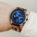 Die CLASSIC Sailor hat ein schlankes und elegantes Gehäuse und verfügt über eine einzigartige Mondphasenanzeige und zwei zusätzliche Hilfszifferblätter. Die aus ostafrikanischem Kosso-Holz gefertigte Uhr hat ein blaues Zifferblatt und goldene Details. Die
