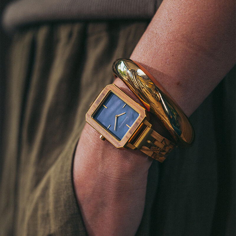 The Elegance Blue Pearl is crafted from olive wood and stainless steel, featuring a blue mother-of-pearl dial with brushed gold metal details.