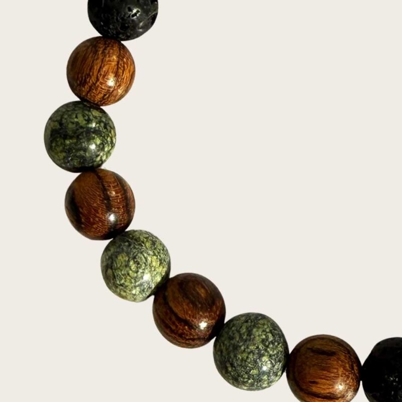 Made with rosewood beads, volcanic beads, dark green natural stone beads, and a matte black brass closure. Adjustable, with 8mm beads to fit most wrist sizes.