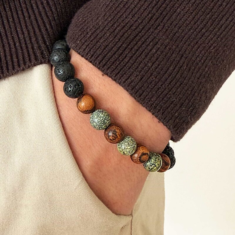 Made with rosewood beads, volcanic beads, dark green natural stone beads, and a matte black brass closure. Adjustable, with 8mm beads to fit most wrist sizes.