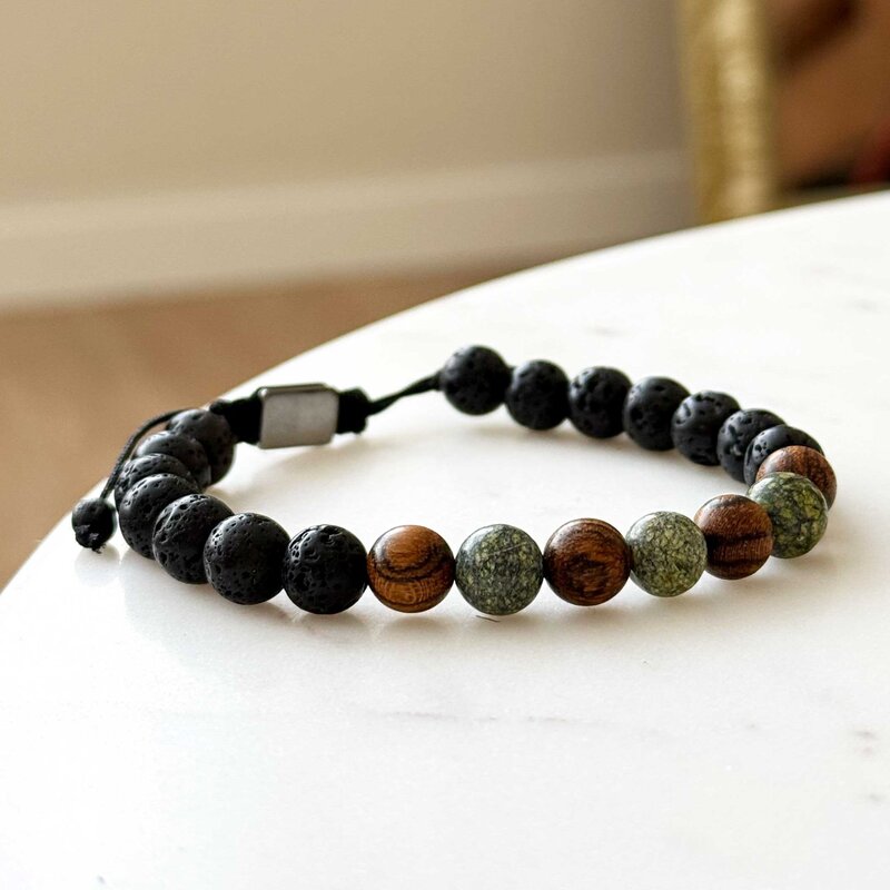 Made with rosewood beads, volcanic beads, dark green natural stone beads, and a matte black brass closure. Adjustable, with 8mm beads to fit most wrist sizes.
