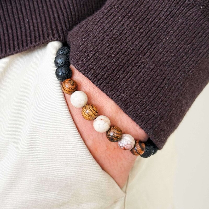 Made with rosewood beads, volcanic beads, dark green natural stone beads, and a matte black brass closure. Adjustable, with 8mm beads to fit most wrist sizes.