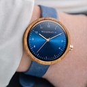La NORDIC Malmo Navy de diamètre 36 mm est sculptée dans du bois de Kosso et présente un cadran bleu ainsi que des détails dorés. Fabriquée à la main à partir de bois d’origine durable, elle s’associe à une courroie en cuir bleu marine, vegan et durable.