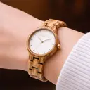 AURORA-kollektionen andas frisk luft från den Skandinaviska naturen och den oöverträffade vyn av himlen. Denna lättviktsklocka är tillverkad av Europeiskt Olivträ, ackompanjerad av en ljus urtavla i rostfritt stål med guldig accent och lysande guldiga det