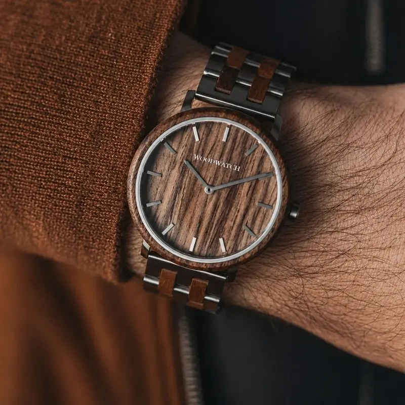 Ein modernes, minimalistisches Design mit einem zeitlosen Look, der zu jeder Gelegenheit passt. Ausgestattet mit einem dünnen Stahlgehäuse, einer Lünette aus Walnussholz und einem Zifferblatt. Im Lieferumfang ist ein neues Armband enthalten, das von Grund