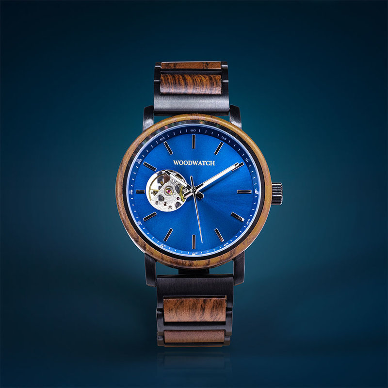 ساعة  The Open-Heart Blue Breeze  مصنوعة من خشب التايجروود وتتميز بقرص أسود مع تفاصيل معدنية سوداء.