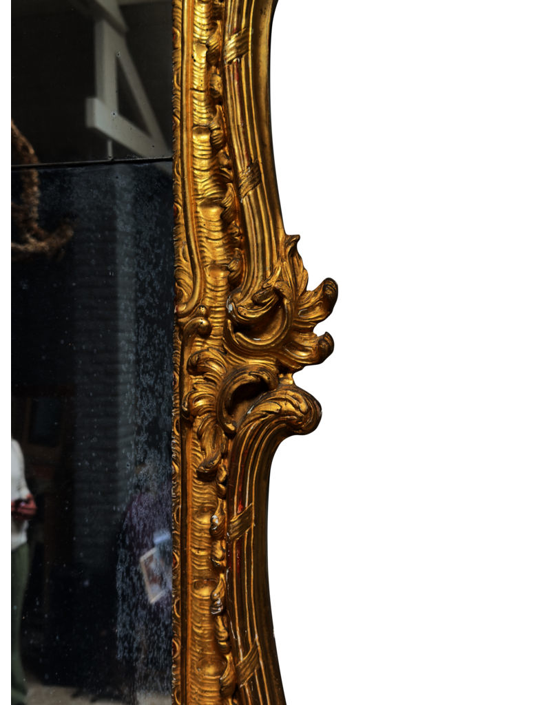 Maison Leon Van den Bogaert Miroir Régence en bois doré avec glace d'origine, décor rocaille sculpté et riche patine dorée