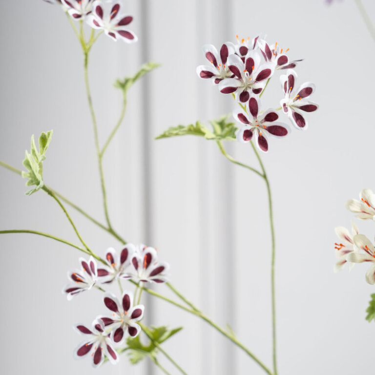 Kunststeel Geranium met witroze zijden bloemen en groene bladeren is een kunststeel met een natuurgetrouwe uitstraling en een lengte van 94 cm.