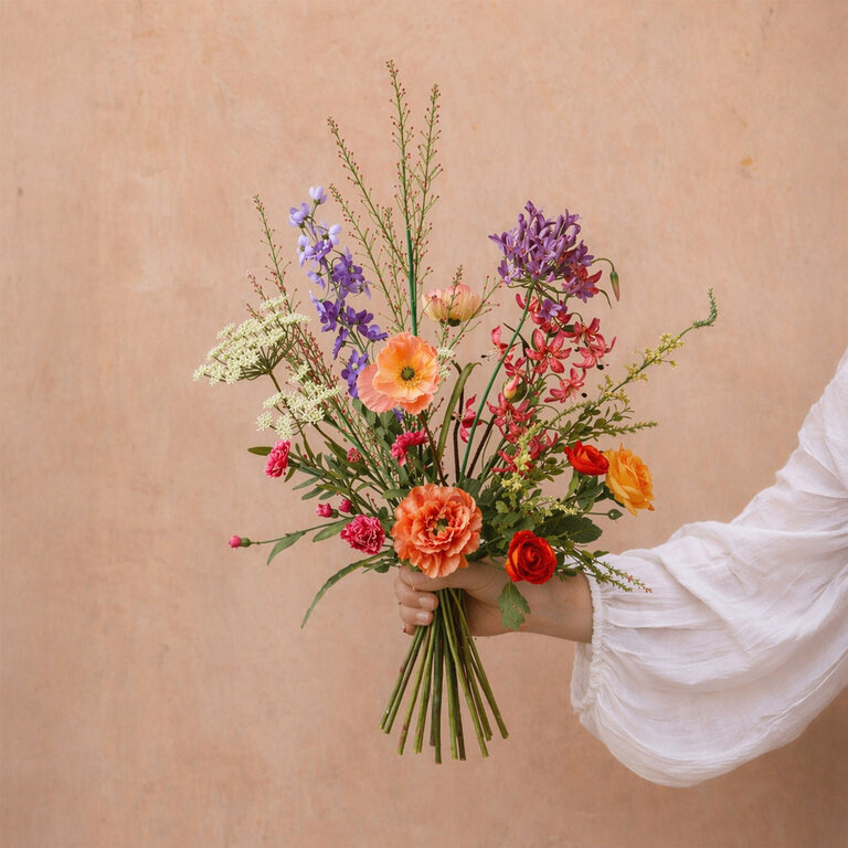 Zijden bloemen boeket Zayna Noor is een levendig en bont veldboeket van kunstbloemen in roze, oranje, paarse, witte en gele tinten.