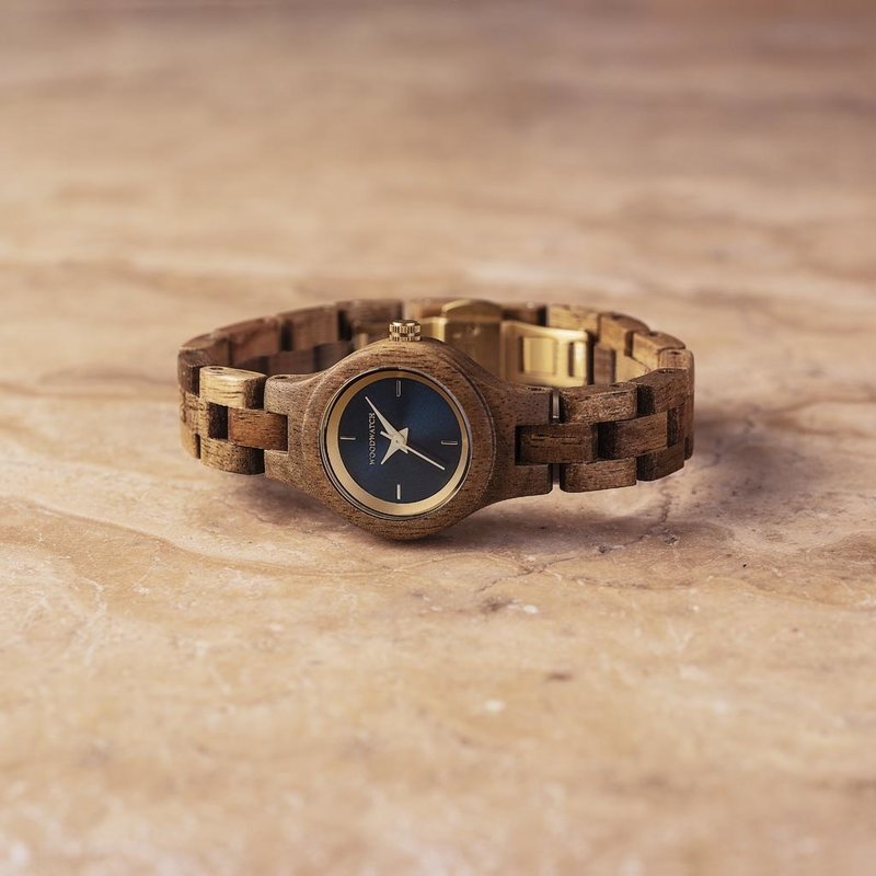 The Bellflower watch from the FLORA Collection consists of acacia wood that has been hand-crafted to its finest slenderness. The Bellflower features a dark navy blue dial with golden colored details.