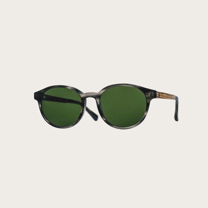 The SOHO Heritage Camo features an oval grey tortoise frame with green camo lenses. Composed of durable Italian Mazzucchelli bio-acetate with hand-finished natural zebrawood temples and tortoise acetate tips. Bio-acetate is made from cotton and organic re