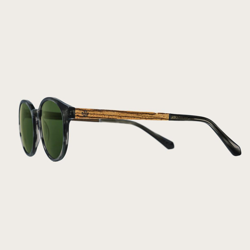 The SOHO Heritage Camo features an oval grey tortoise frame with green camo lenses. Composed of durable Italian Mazzucchelli bio-acetate with hand-finished natural zebrawood temples and tortoise acetate tips. Bio-acetate is made from cotton and organic re