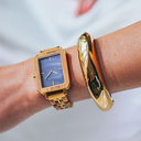 The Elegance Blue Pearl is crafted from olive wood and stainless steel, featuring a blue mother-of-pearl dial with brushed gold metal details.